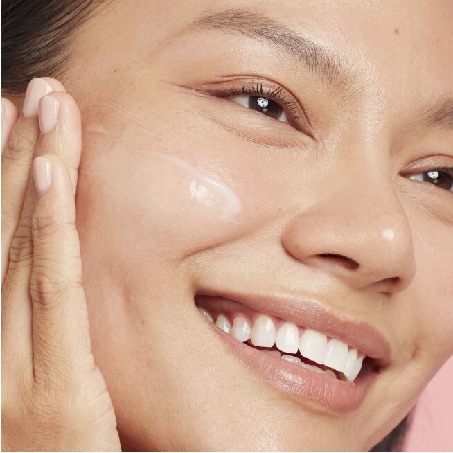 Woman smoothing serum on her face